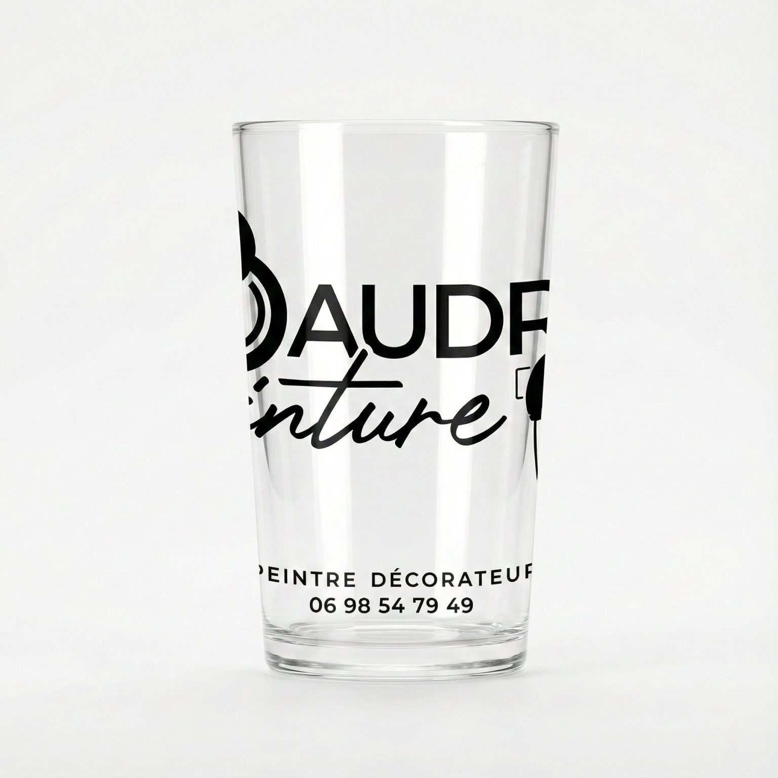 Verre transparent personnalisé avec le logo “Baudry Peinture”, texte noir incluant contact, présenté sur fond clair.